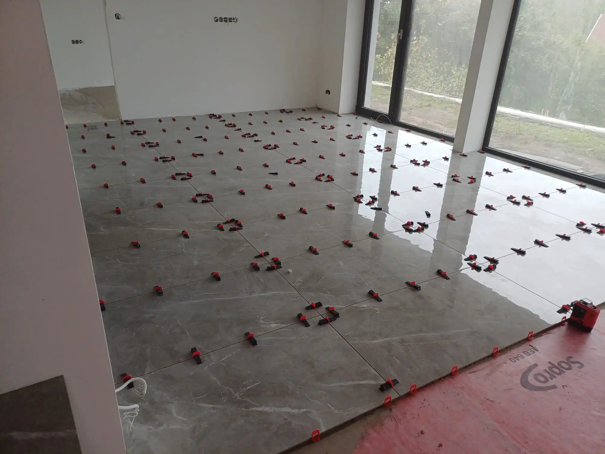 Beltéri padlóburkolás szintező klipszekkel egy világos helyiségben.